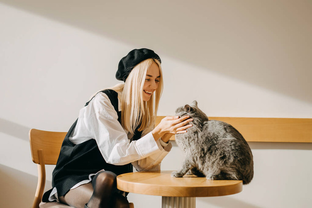 Mladá blondýna žena hraje s kočkou v kavárně. - Fotografie, Obrázek