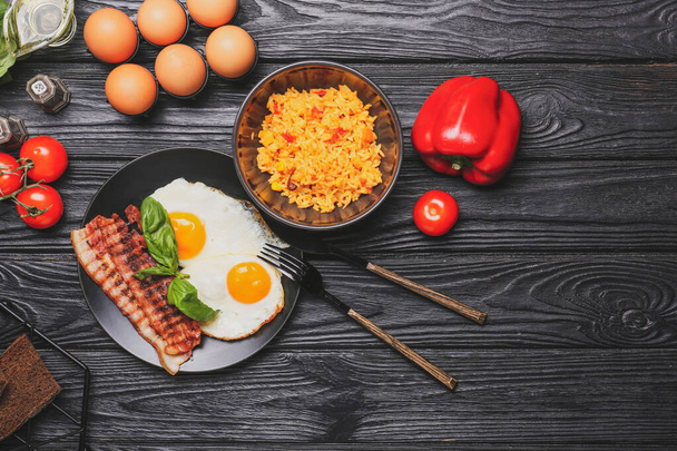 Plate with tasty eggs and bowl with rice on wooden background - Фото, зображення