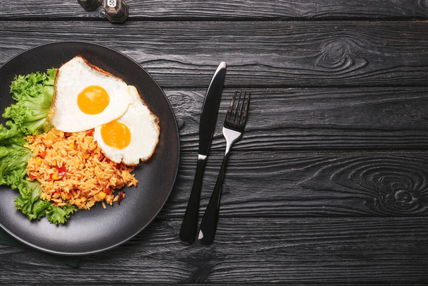 Bord met lekkere eieren en rijst op donkere houten ondergrond - Foto, afbeelding