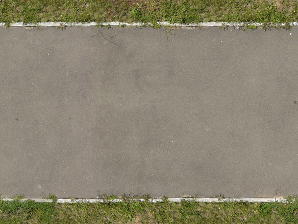 Textur der neuen, asphaltierten Straße in Grautönen mit Gras an den Rändern. - Foto, Bild