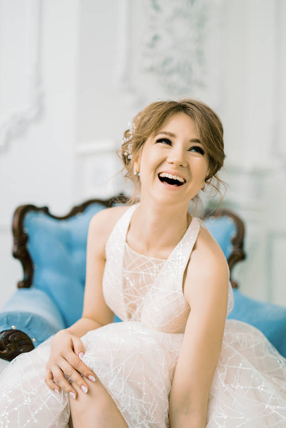 Amazing and emotional bride laughs and smiles. A girl in a wedding dress is waiting for the groom. - Фото, изображение