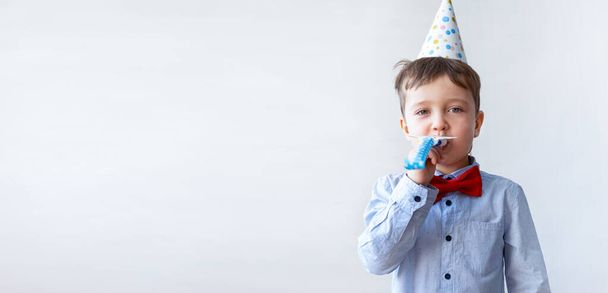 Mignon petit garçon en nœud papillon rouge avec chapeau de fête coup corne de fête. Fête d'anniversaire. - Photo, image
