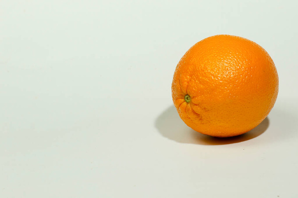 Ένα πορτοκάλι στα δεξιά ένα λευκό φόντο με μια σκιά σταγόνα - Φωτογραφία, εικόνα