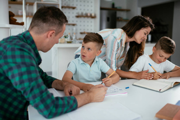 A szülők segítenek a gyerekeknek a házi feladatukban. Kisfiúk otthon tanulnak.. - Fotó, kép