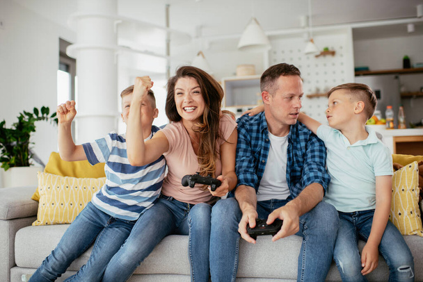 Père et mère s'amusent en jouant à des jeux vidéo avec des enfants à la maison. - Photo, image