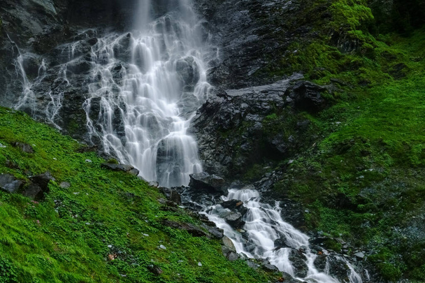 geweldige waterval met vele treden met veel rotsen en groene planten in de bergen - Foto, afbeelding