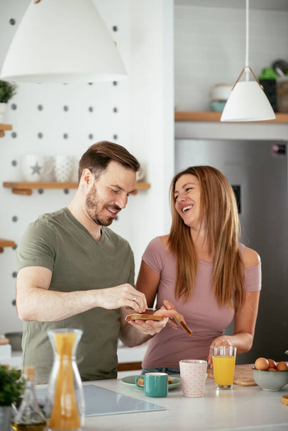 Young couple making sandwiches at home. Loving couple enjoying in the kitchen. - Φωτογραφία, εικόνα