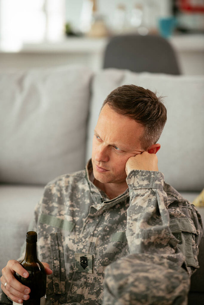 Soldado deprimido com garrafa na sala de estar. Dependência alcoólica. - Foto, Imagem