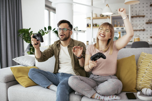 Férj és feleség videojátékoznak joystickokkal a nappaliban. A szerető pár otthon videojátékozik.. - Fotó, kép