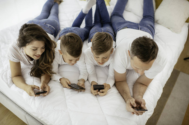 Family using mobile phones. Parents and kids using smart phones at home. - Photo, Image