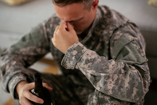 расстроенный военный пьет алкоголь дома - Фото, изображение