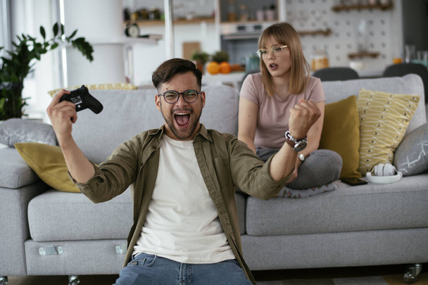 Beau jeune couple jouant à des jeux vidéo à la maison. - Photo, image