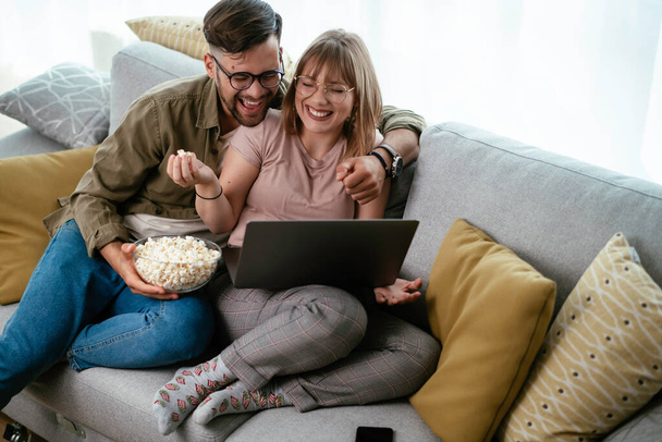 Young couple watching movie on laptop. Loving couple enjoying at home. - Foto, Imagem