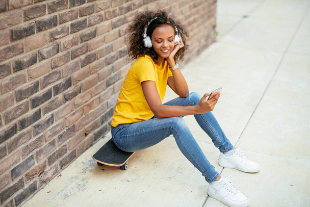 Giovane pattinatrice africana scattare selfie e ascoltare musica per strada - Foto, immagini