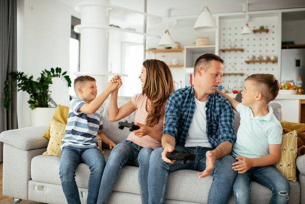  Happy loving couple are playing video games with kids at home. - Foto, afbeelding