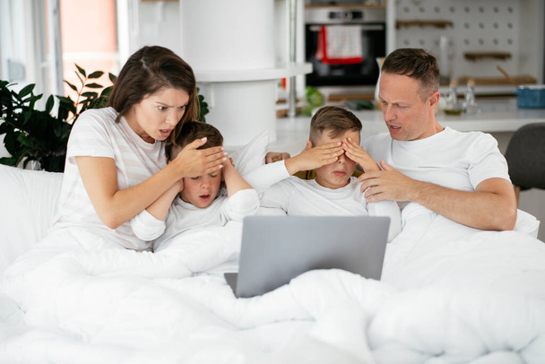 Belos pais com crianças desfrutando em casa. Jovem família assistindo filme no laptop - Foto, Imagem