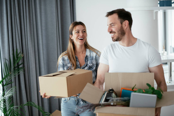 Boyfriend and girlfriend are moving in a apartment. Young couple are unpacking their belongings. - Foto, imagen