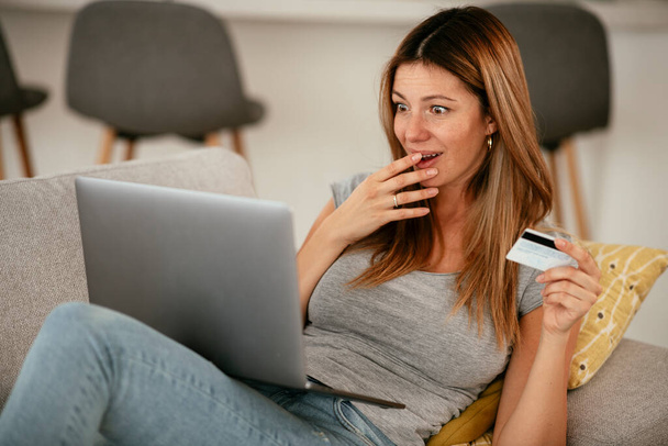 Młoda kobieta używająca karty kredytowej i laptopa w domu. Piękna kobieta kupuje online. - Zdjęcie, obraz