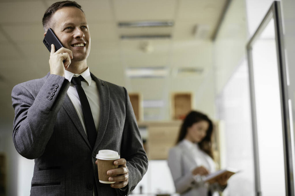 Бизнесмен обсуждает работу по телефону. Молодой бизнесмен разговаривает по телефону в офисе. - Фото, изображение