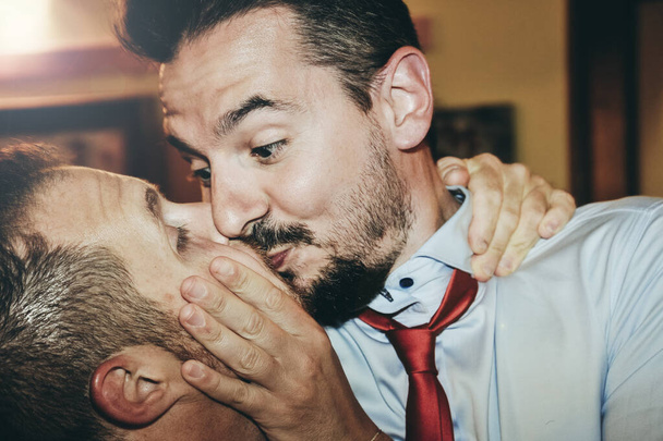 Loving gay paar zoenen hartstochtelijk op de bruiloft feest - twee knappe mannen met romantische kus binnen - LGBT bruiloft en rechten concept - Foto, afbeelding