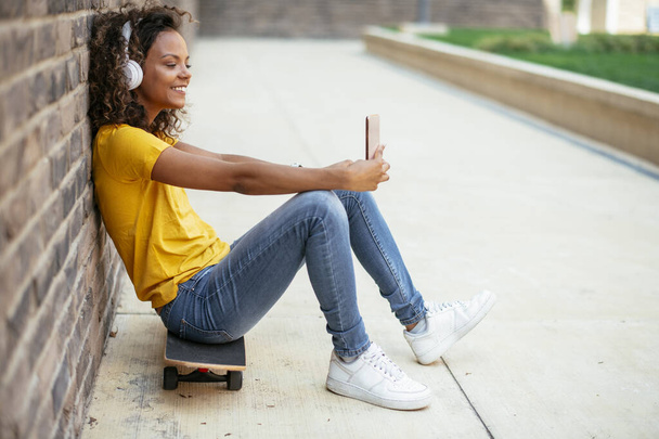 Jovem patinadora africana tomando selfie e ouvir música na rua - Foto, Imagem