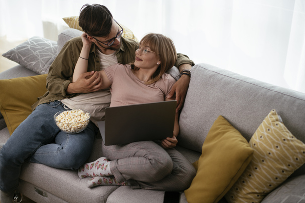 Dizüstü bilgisayarda film izleyen genç bir çift. Sevgili çift evde eğleniyor.. - Fotoğraf, Görsel