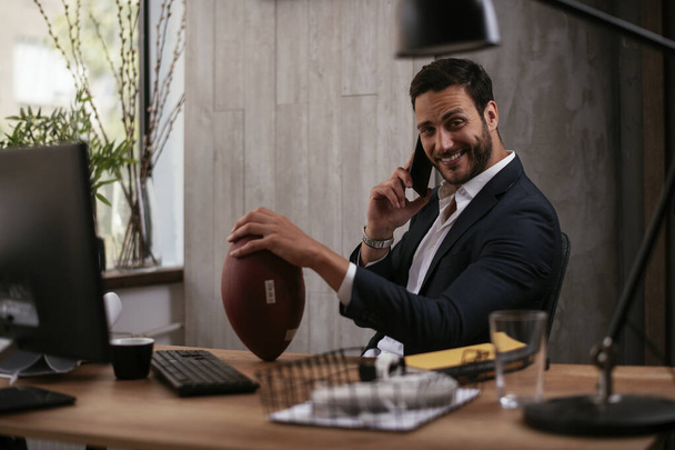 Hezký obchodník v obleku pracuje v kanceláři a drží míč - Fotografie, Obrázek