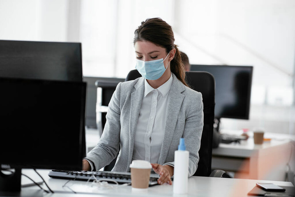 Belle femme d'affaires avec masque médical travaillant au bureau. Concept Covid-19. - Photo, image