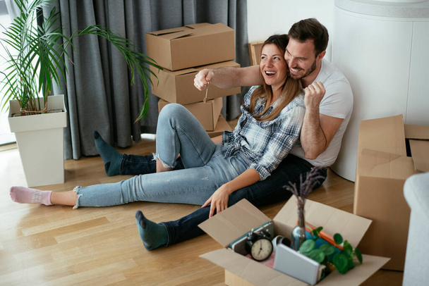 Парень и девушка переезжают в квартиру. Молодая пара распаковывает свои вещи. - Фото, изображение