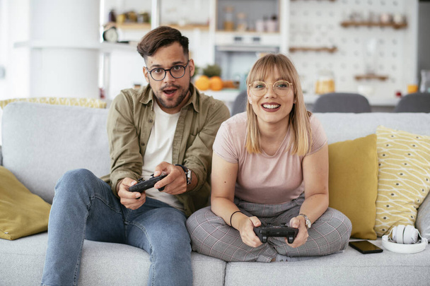 Красивая молодая пара играет в видеоигры дома. - Фото, изображение