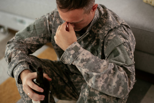 upset military man drinking alcohol at home - Photo, Image