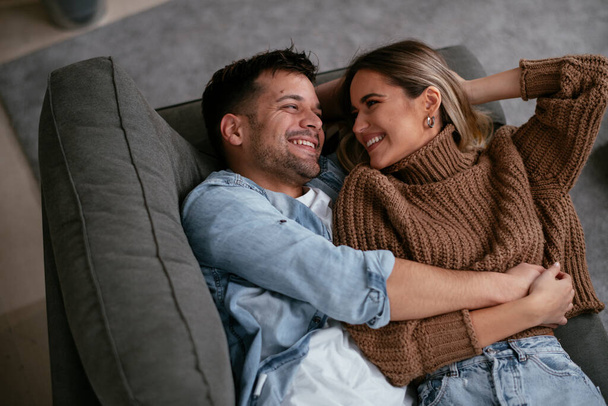 Jeune couple aimant se détendre sur le canapé ensemble. Couple heureux appréciant à la maison. - Photo, image