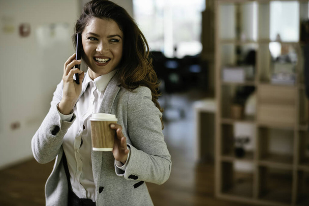 Красивая деловая женщина разговаривает по мобильному телефону в офисе. Молодая предпринимательница, работающая в офисе. - Фото, изображение