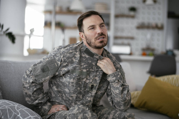 Masentunut sotilas istuu sohvalla. Nuori sotilas, jolla on traumaperäinen stressihäiriö. - Valokuva, kuva