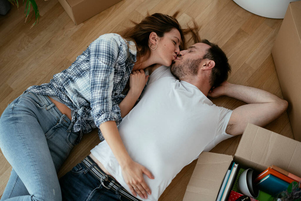 Boyfriend and girlfriend are moving in new apartment. Young couple lie on the floor - Fotoğraf, Görsel