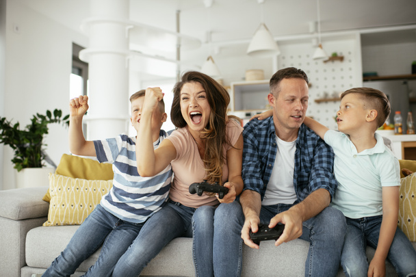 Pai e mãe se divertindo enquanto joga jogos de vídeo com crianças em casa. - Foto, Imagem