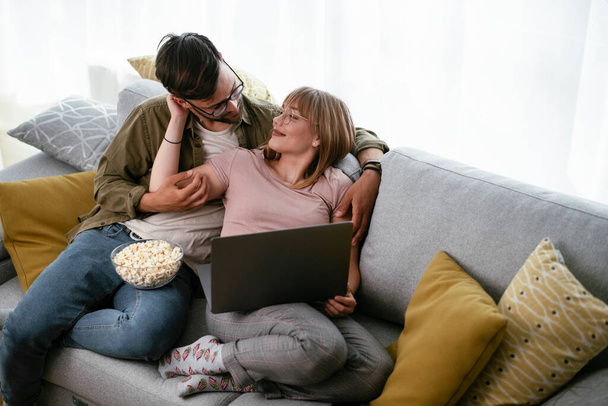 Fiatal pár filmet néz laptopon. Szerető pár, akik otthon élvezik. - Fotó, kép