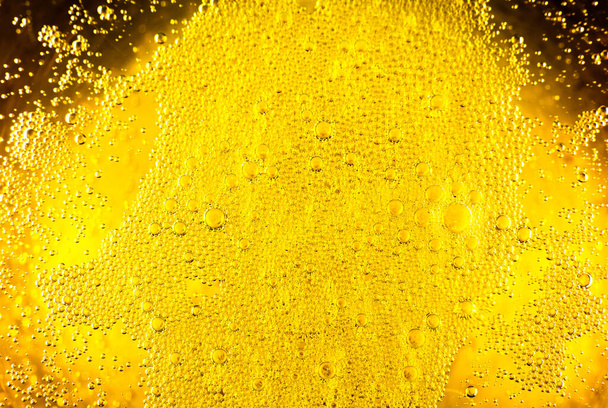 Folyékony arany-sárga benzin buborékok háttér sör vagy pezsgő üveg. Közelről, makró lövés.. - Fotó, kép