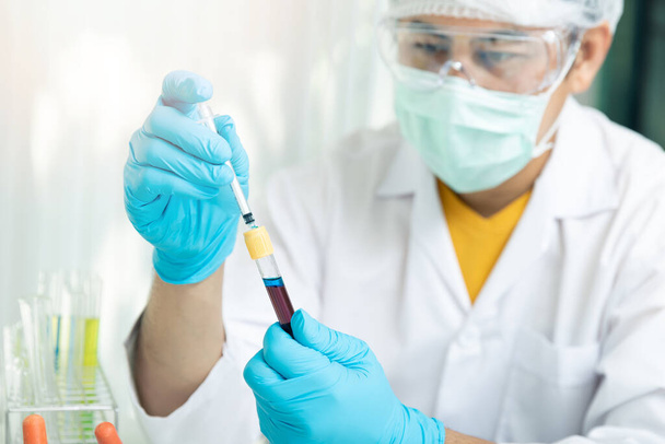 Il ricercatore o gli scienziati caricano il liquido nel campione di sangue in provetta. I ricercatori stanno sviluppando vaccini e medicinali per il trattamento del virus COVID-19. - Foto, immagini