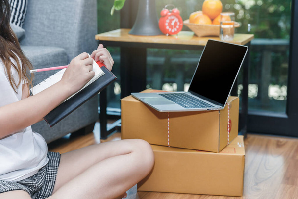 Succesvolle ondernemer zakenvrouw met online verkoop en Pakket verzending in haar kantoor. Vrouw controleert bestelling op notebook. - Foto, afbeelding