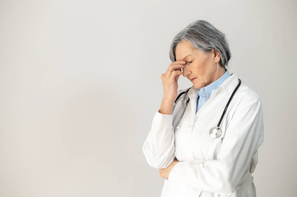 Side view of a stressed senior female doctor - Фото, зображення