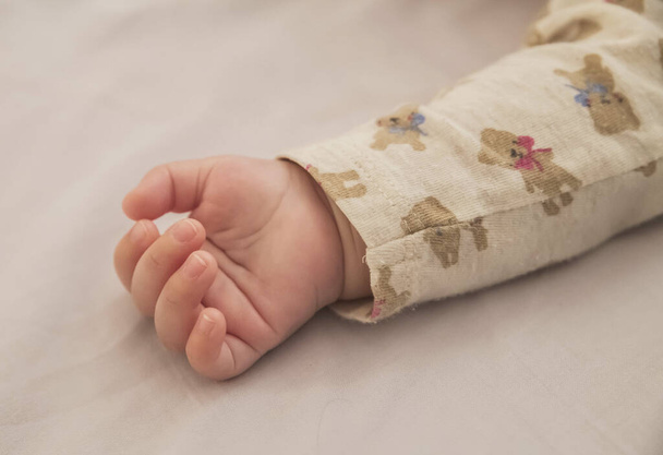 petite main d'un bébé endormi dont la manche représente des ours jouets - Photo, image