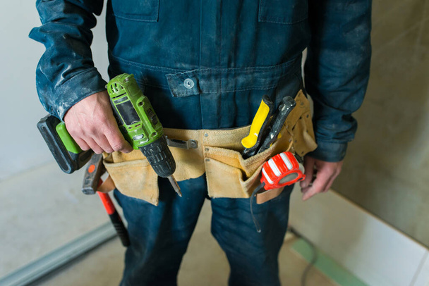 İşçi inşaat aletlerini elinde tutuyor.. - Fotoğraf, Görsel