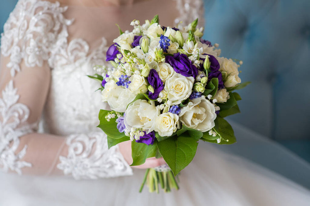 Nevěsta sedí a drží svatební kytici zblízka - Fotografie, Obrázek