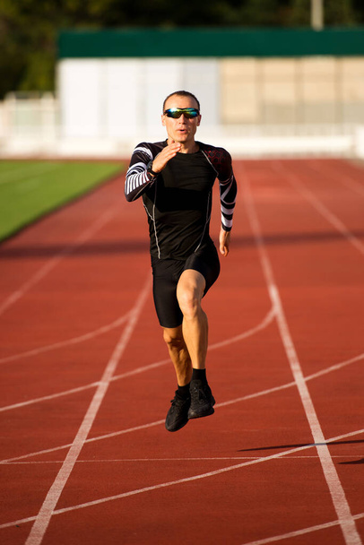 Runner running along the track in the stadium - Фото, изображение