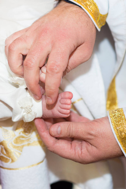 司祭は洗礼中に赤ん坊の足に触れる - 写真・画像