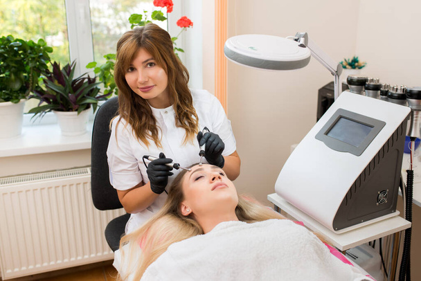 schoonheidsspecialiste doet massage met microstromen in de kliniek - Foto, afbeelding