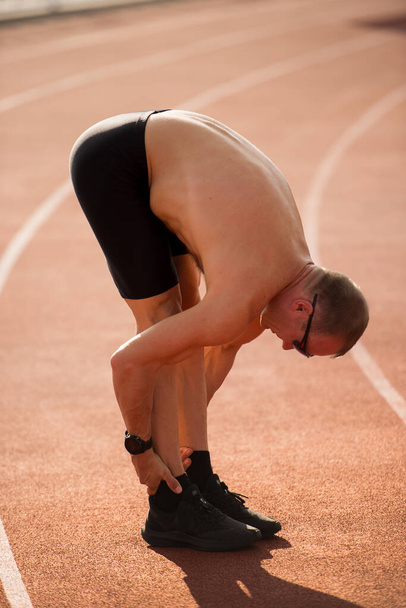 De atleet strekt zich uit op de baan - Foto, afbeelding