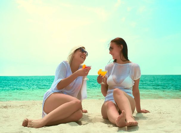 Two girls having picnic on tropical beach. Beautiful women with  cocktails  - Valokuva, kuva