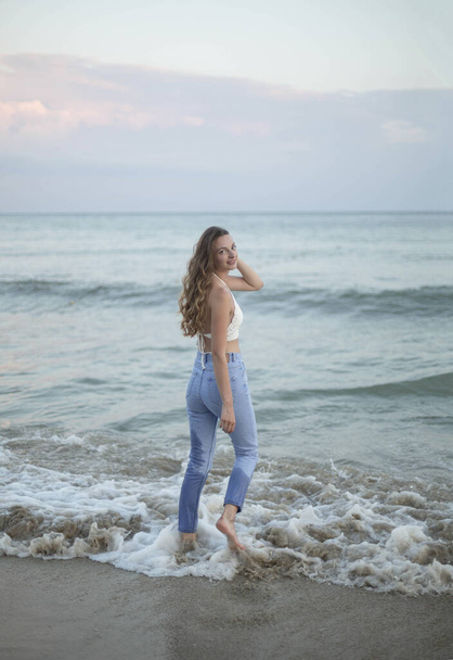 Молодая стройная красивая женщина на закатном пляже - Фото, изображение